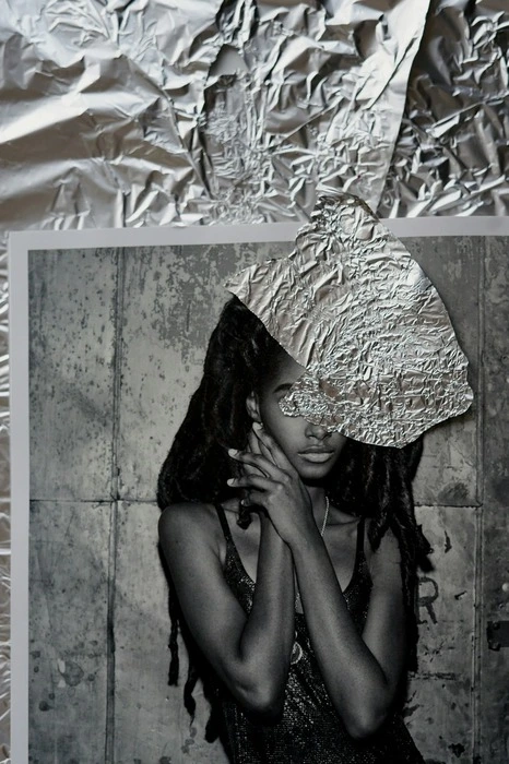 Mural com foto de mulher e um papel laminado sobre seus olhos. 